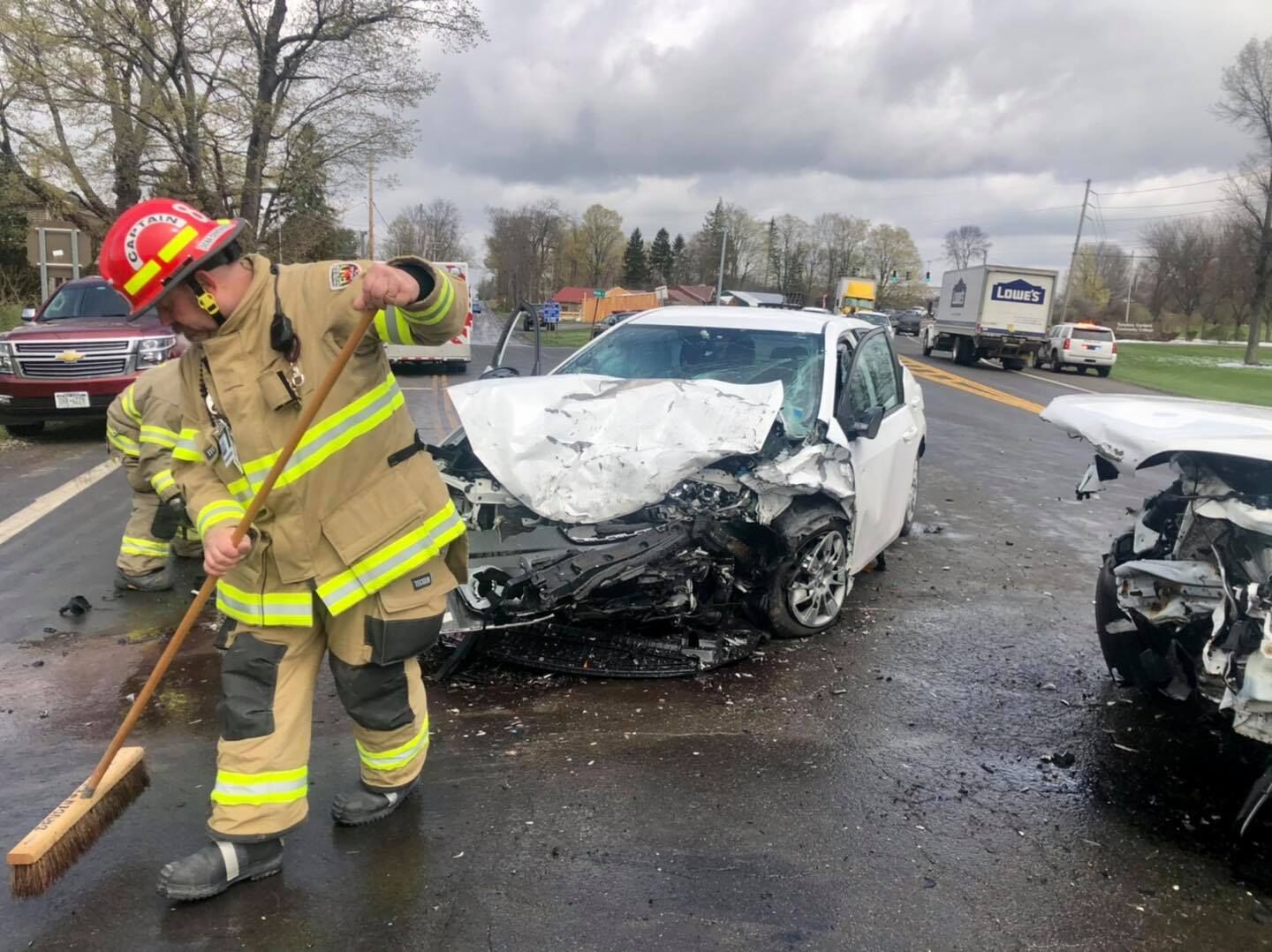 A firefighter sweeps away debris from a head-on car accident that took place near North Road and Cortland Road in Dryden on April 22.